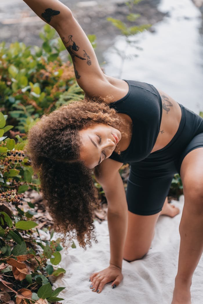 Woman stretching in activewear outdoors by a river, emphasizing wellness and nature.